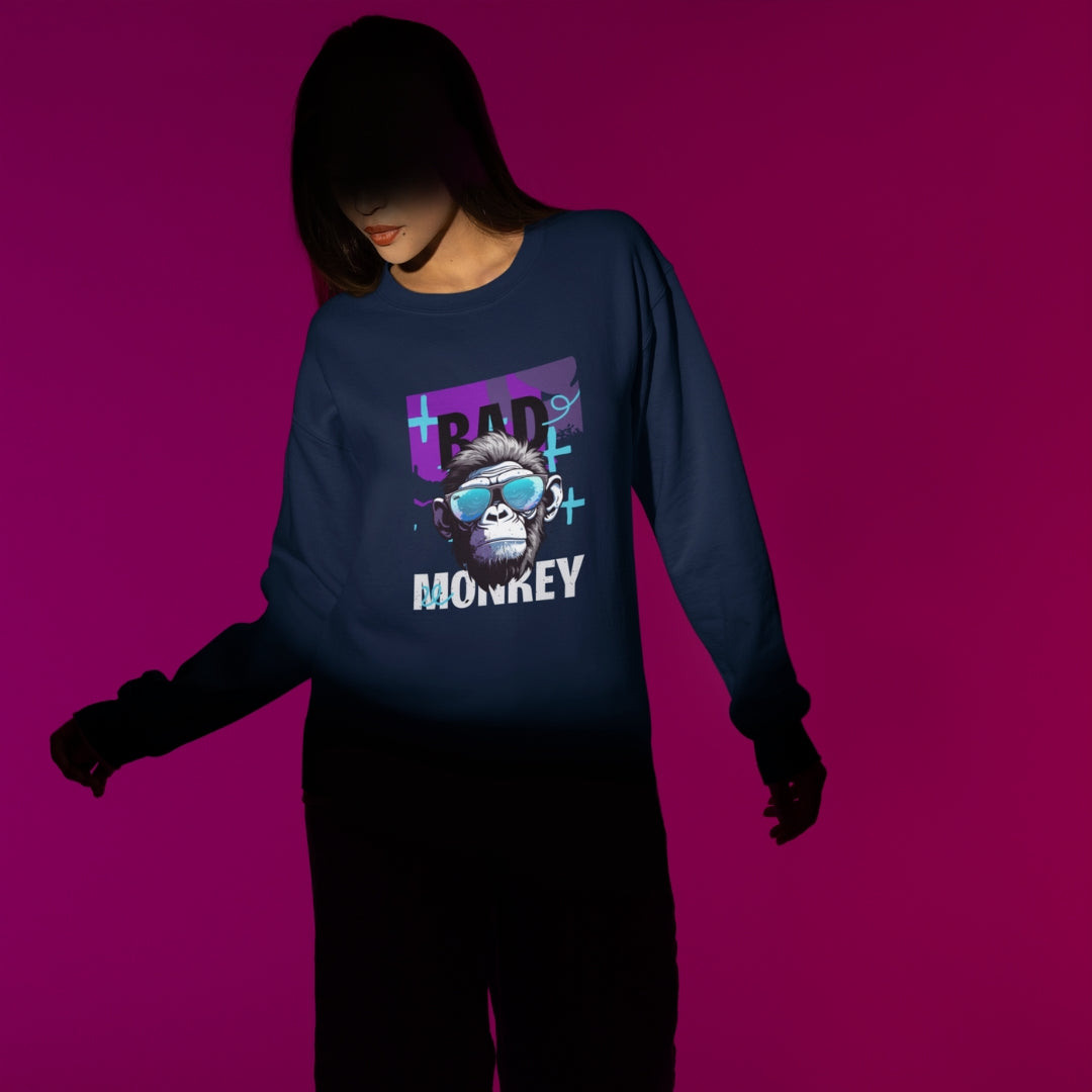 Women wearing a navy sweatshirt with a monkey head with sunglasses design and the text bad monkey in a studio shooting.